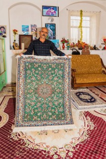 Iranian man showing a handmade carpet