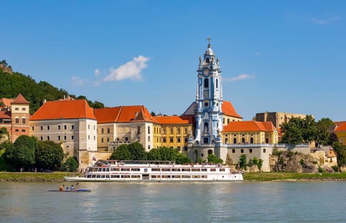 Excursion boat on the Danube in front of the baroque church of the monastery Duernstein
