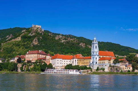 Excursion boat on the Danube in front of the baroque church of Duernstein Abbey