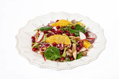 Served salad on a porcelain plate with orange slices
