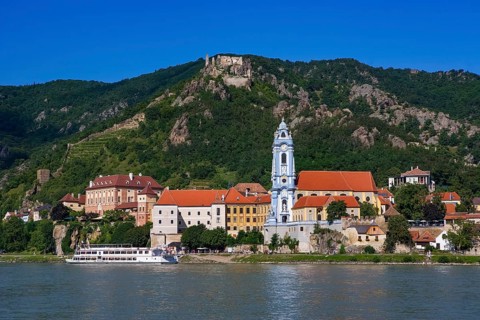 Excursion boat on the Danube in front of the baroque church of Duernstein Abbey