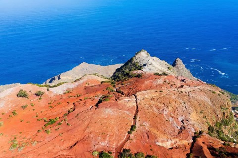 Eroded mountain slope with red earth at the coast