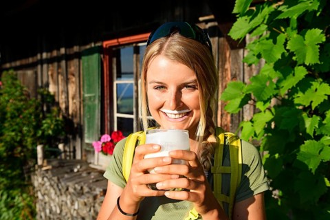 Young female hiker drinks buttermilk at the Kraftalm