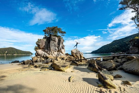 Young man standing with outstretched arms on a rock