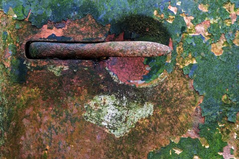 Flaked off colourful paint on an old car door
