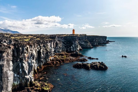 Orange lighthouse of Oendverdarnes stands on cliffs