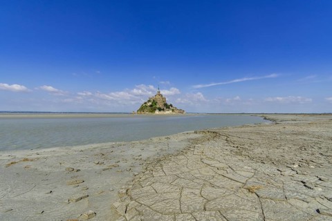 View over dried mud at the edge of the salt marshes at low tide on Mont-Saint-Michel
