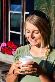 Young female hiker drinks buttermilk at the Kraftalm