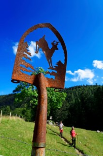 Hikers next to an artistically decorated shovel at the Chiemhauser Alm