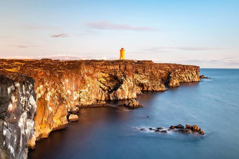 Orange lighthouse of Oendverdarnes stands at cliff coast