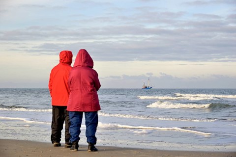 Two people on the beach watching a crab cutter off Norderney