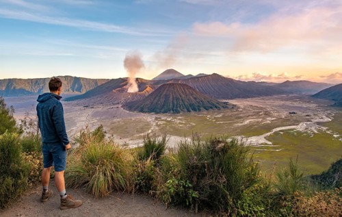 Young man in front of volcanic landscape at sunset