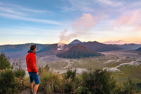 Young man in front of volcanic landscape at sunset