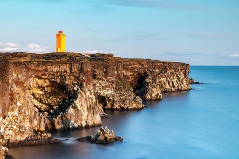 Orange lighthouse of Oendverdarnes stands at cliff coast