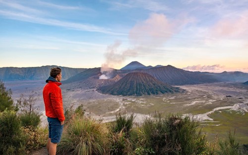 Young man in front of volcanic landscape at sunset
