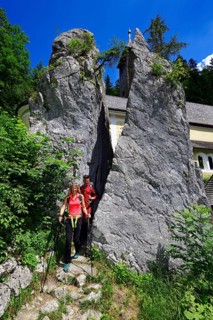 Hikers walk through the split rock at Klobenstein