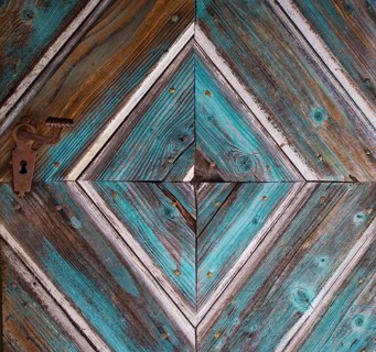 Old wooden house door with diamond-shaped pattern on a historical farmhouse