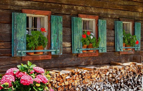Old farmhouse with flower windows with geraniums