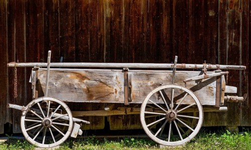 Historical cart stands in front of a barn