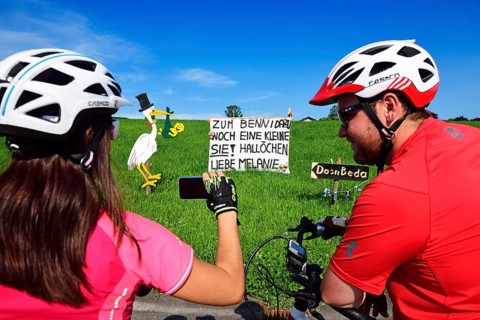 Cyclists photographing Rattling stork and banner as a welcome for a newborn child