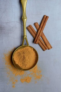 Cinnamon powder in brass ladle and cinnamon sticks