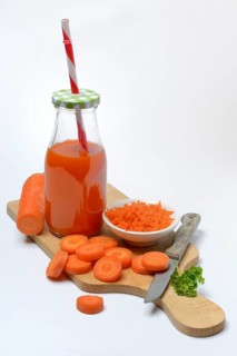 Carrot juice in bottle and carrot slices