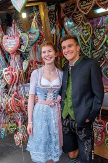 Young couple in traditional traditional traditional traditional traditional traditional traditional traditional traditional traditional costume in front of gingerbread hearts