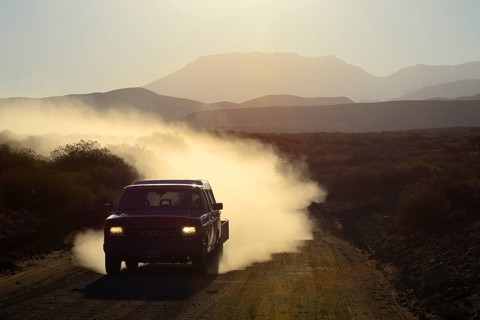 All-terrain vehicle with dust cloud on track through volcanic lunar landscape