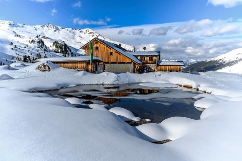 Snowy Lizumer Hut with small mountain lake in winter