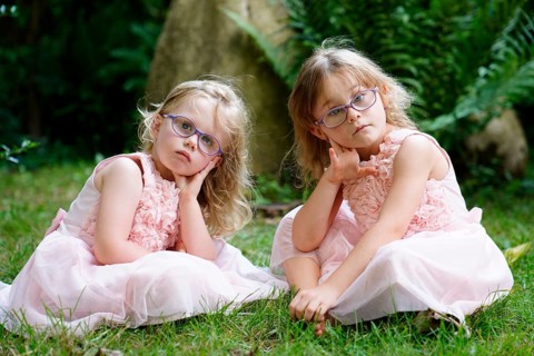Two sisters in pink dress sitting in the garden (6 years old