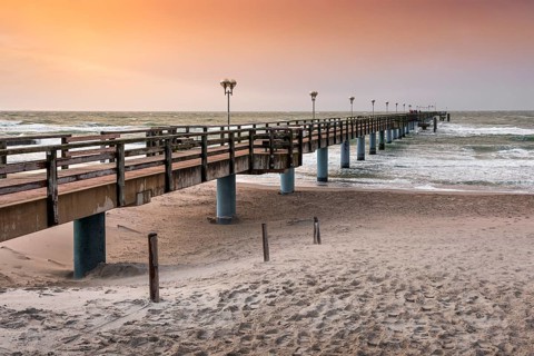 Pier on the beach of the Baltic Sea at sunset