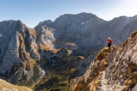 Mountaineer with climbing helmet running on a steep mountain slope