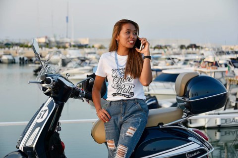 Woman with Vespa 125 Primavera in the port of Penelope
