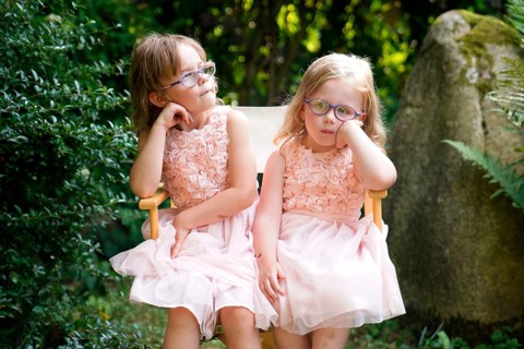 Portrait of two sisters sitting together on a garden chair (6 years old