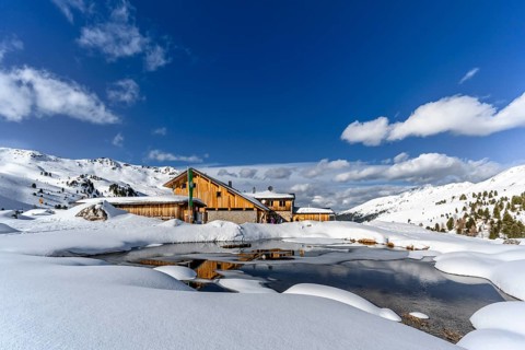 Snowy Lizumer Hut with small mountain lake in winter