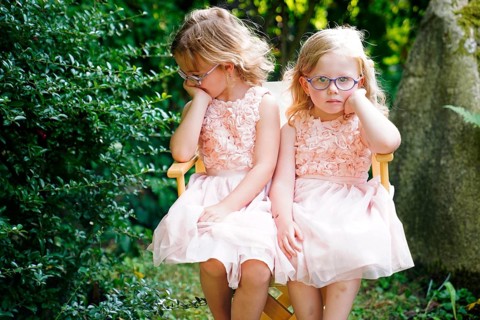 Portrait of two sisters sitting together on a garden chair (6 years old