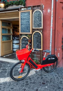 Red JUMP electric rental bike outside Italian restaurant with handwritten blackboard menu