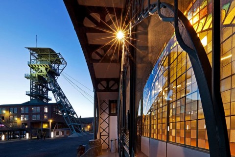 Illuminated machine hall with winding tower in the evening