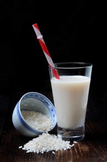 Rice milk in glass with drinking straw and rice grains