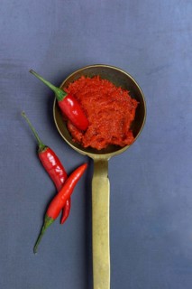 Red Thai curry paste in brass ladle and chilli peppers