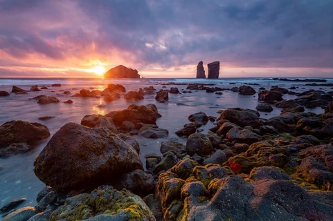 Sunset on a stony coast with huge rocks in the Atlantic Ocean