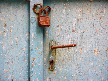 Old door lock with door handle on weathered wooden door
