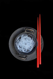 Asian glass noodles in pot and red chopsticks