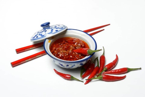 Crushed chilli peppers in oil in shell and red chopsticks