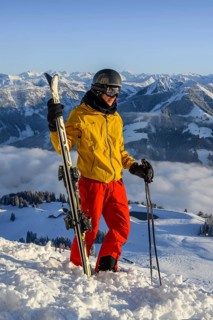 Skier stands at the ski slope and holds ski