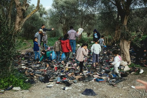 Refugees look for shoes from a pile of donations