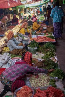 Market woman offer vegetables and sit on the floor