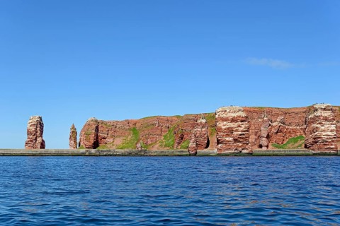 View from the water to the red sandstone rocks with Langer Anna