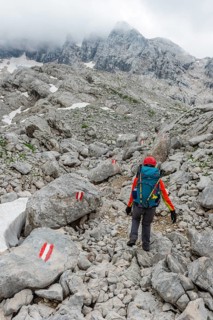 Mountaineer runs through rocky alpine terrain on a marked route