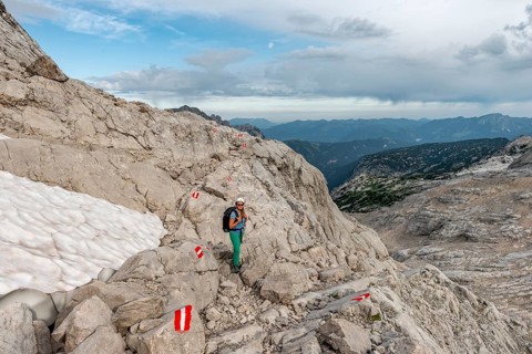 Mountaineer on marked route through rocky alpine terrain